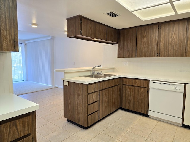 kitchen with kitchen peninsula, dark brown cabinets, white dishwasher, sink, and light tile patterned floors