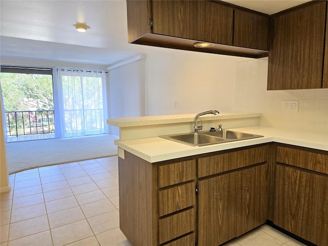 kitchen with kitchen peninsula, light tile patterned floors, decorative backsplash, and sink