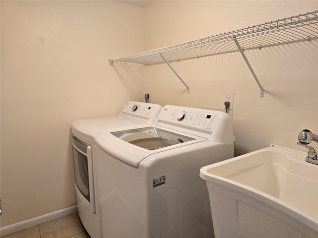 washroom featuring independent washer and dryer, sink, and light tile patterned floors