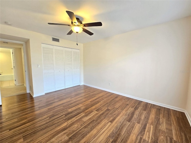 unfurnished bedroom with dark hardwood / wood-style flooring, a closet, and ceiling fan