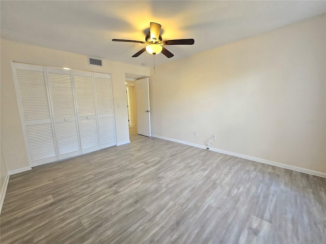 unfurnished bedroom featuring ceiling fan, a closet, and light wood-type flooring