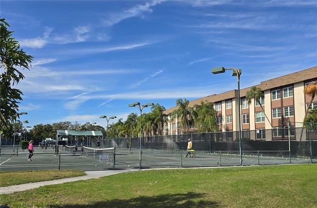 view of tennis court featuring a yard