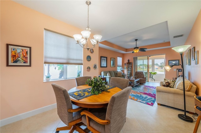 tiled dining area with ceiling fan with notable chandelier and a raised ceiling