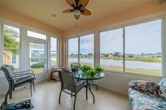 sunroom featuring ceiling fan, a healthy amount of sunlight, and a water view