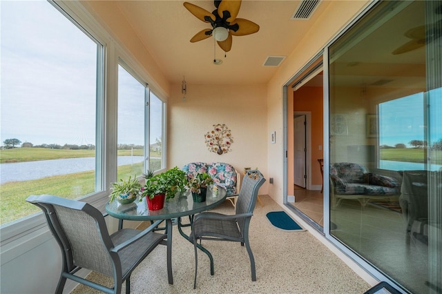 sunroom featuring ceiling fan and a water view