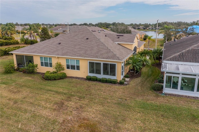 back of house featuring a sunroom, a water view, and a yard