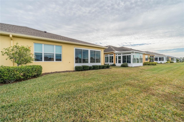 rear view of property featuring a lawn and a sunroom