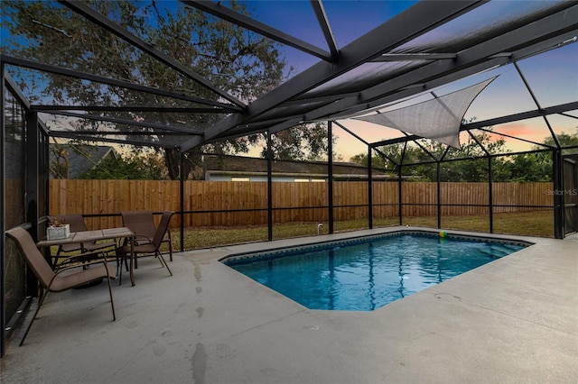 pool at dusk with a patio area and glass enclosure