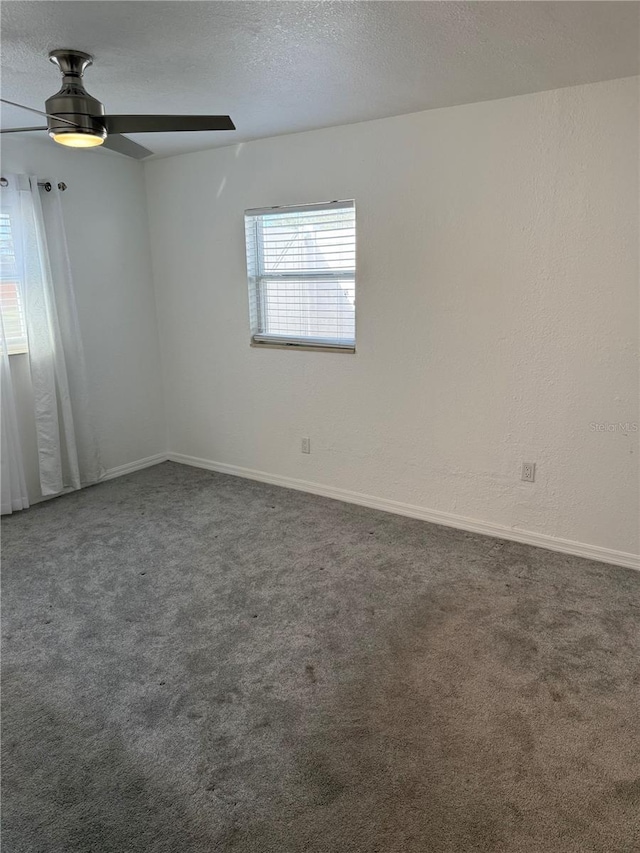 empty room with ceiling fan, dark carpet, and a textured ceiling