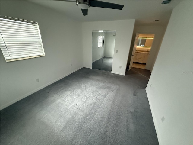 unfurnished bedroom with ceiling fan, connected bathroom, carpet floors, baseboards, and a closet