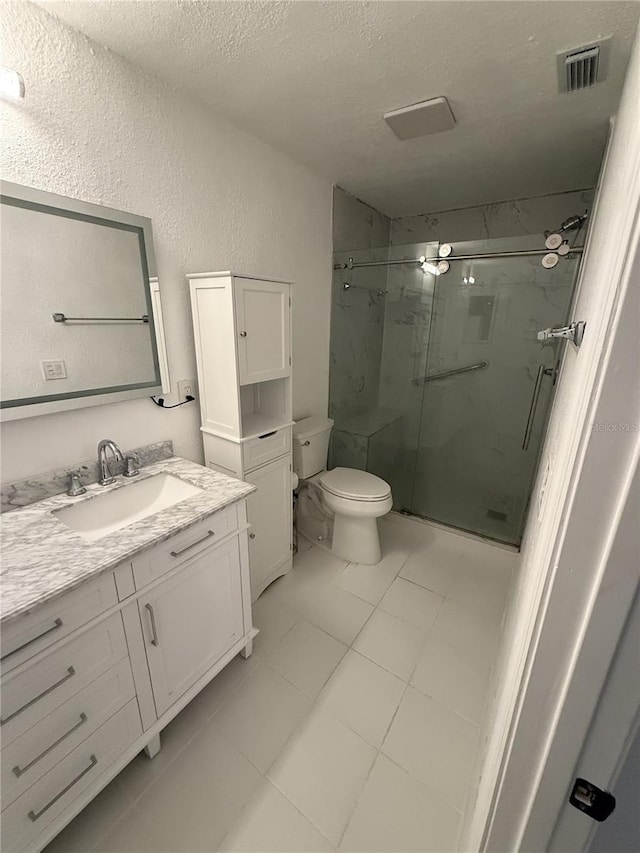 full bathroom featuring a marble finish shower, visible vents, toilet, a textured ceiling, and vanity