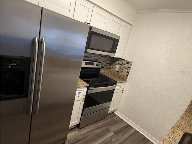 kitchen with dark wood finished floors, crown molding, backsplash, appliances with stainless steel finishes, and white cabinetry