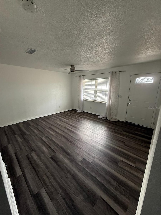 interior space with dark wood-style flooring, ceiling fan, a textured ceiling, and baseboards