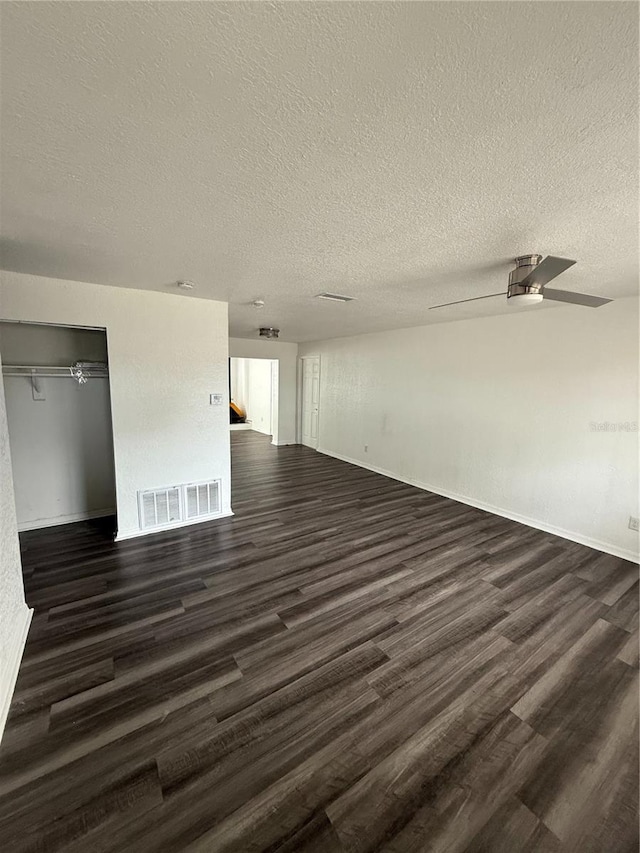 spare room featuring a textured ceiling, dark wood-style flooring, visible vents, and a ceiling fan