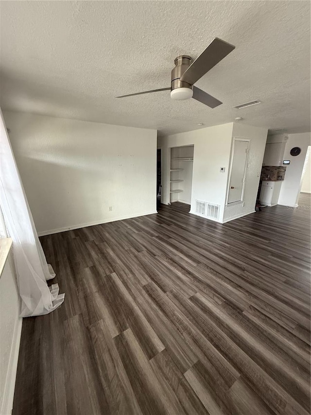 interior space featuring dark wood-style floors, a textured ceiling, visible vents, and a ceiling fan