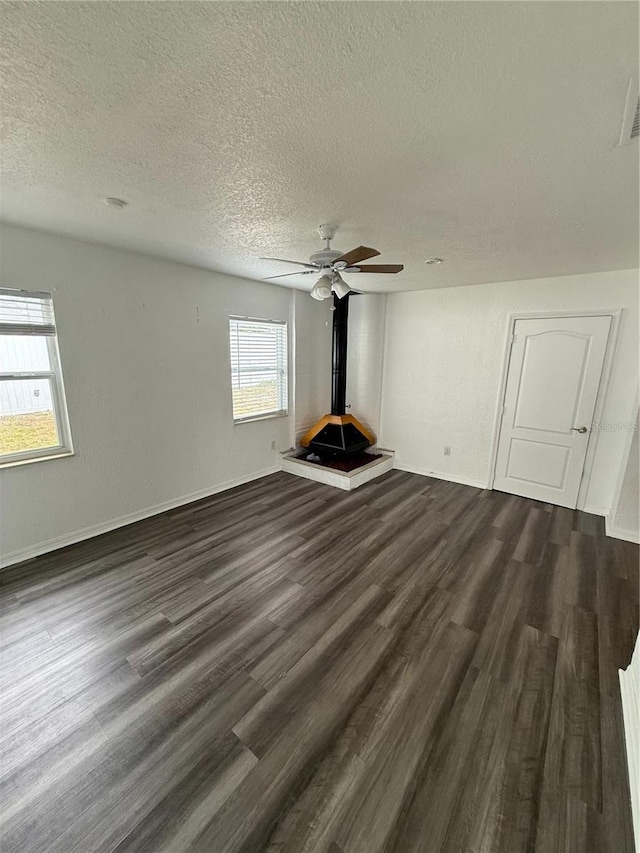 unfurnished living room with ceiling fan, dark wood-style flooring, a textured ceiling, and baseboards