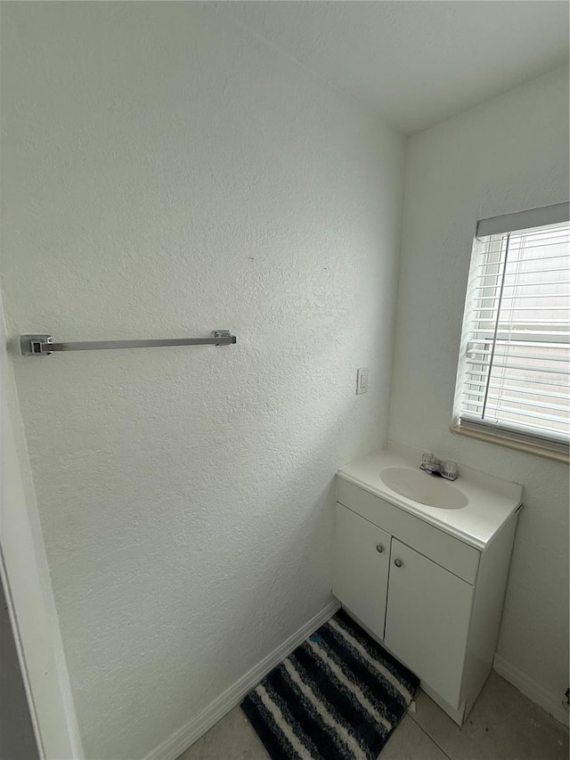 bathroom featuring a textured wall, vanity, and baseboards