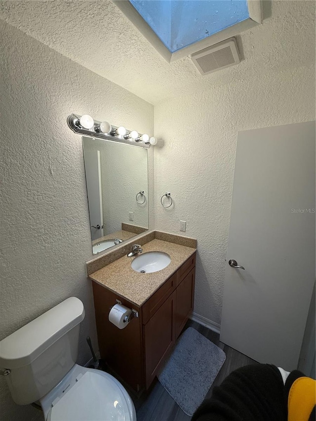 bathroom featuring visible vents, a textured wall, and vanity