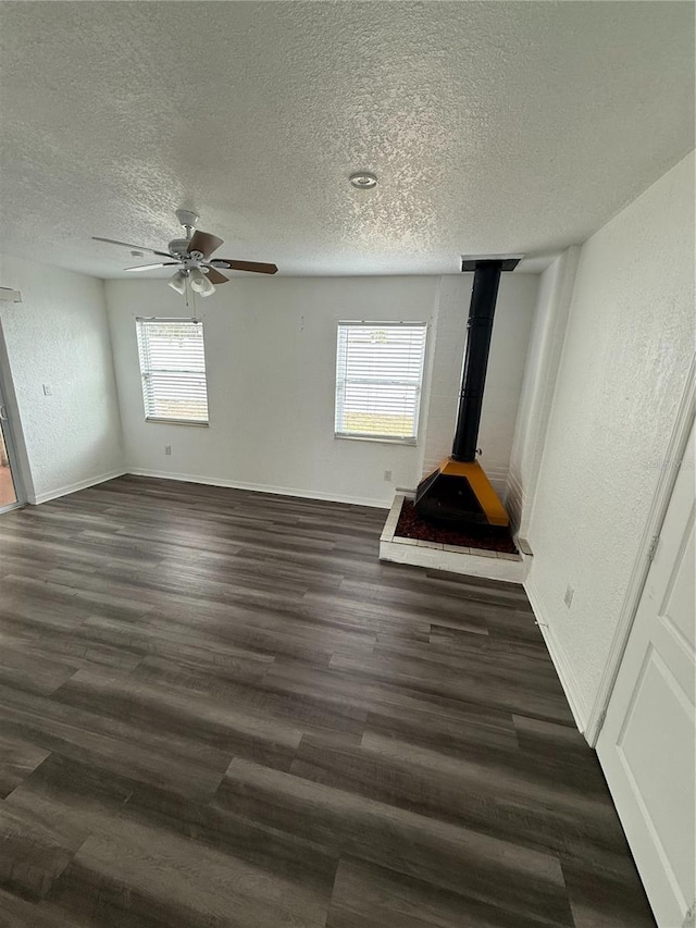 unfurnished bedroom with a textured ceiling, a textured wall, dark wood finished floors, and baseboards