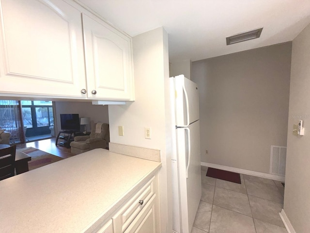 kitchen featuring white refrigerator, white cabinetry, and light tile patterned flooring