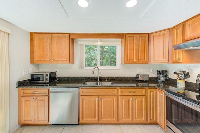 kitchen featuring light tile patterned flooring, sink, dark stone countertops, appliances with stainless steel finishes, and exhaust hood