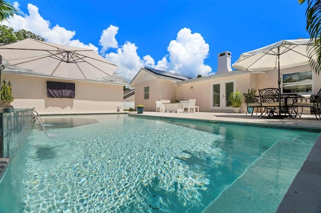 view of pool featuring pool water feature, a patio area, and french doors