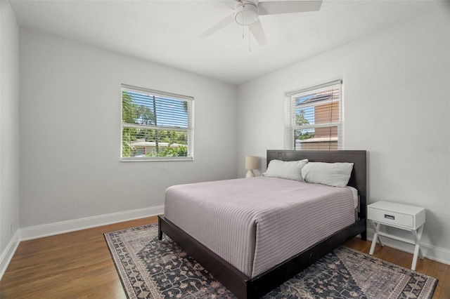 bedroom featuring ceiling fan, dark hardwood / wood-style floors, and multiple windows