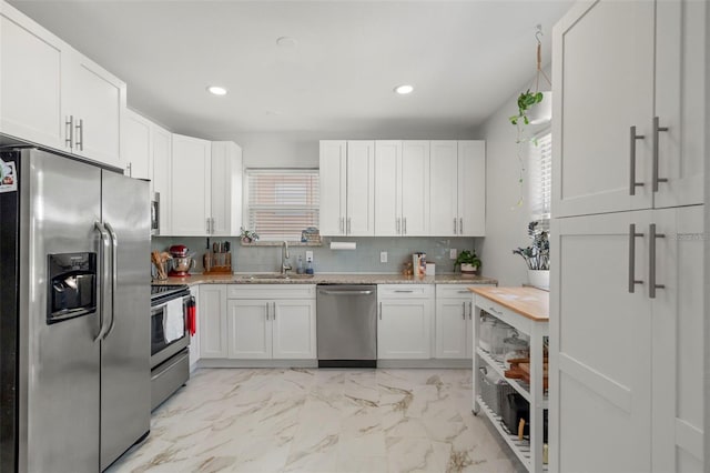 kitchen with backsplash, white cabinets, sink, light stone countertops, and stainless steel appliances