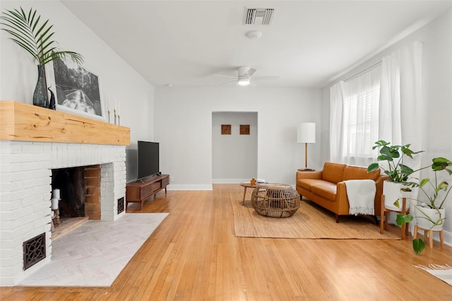 living room featuring hardwood / wood-style flooring, ceiling fan, and a brick fireplace