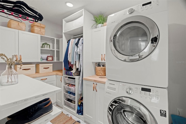 washroom featuring cabinets and stacked washer and dryer