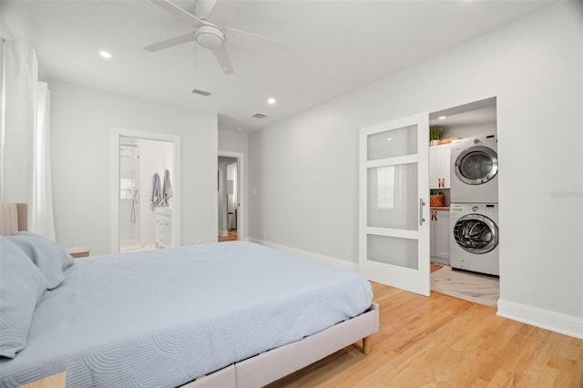 bedroom with connected bathroom, ceiling fan, light hardwood / wood-style floors, and stacked washer / drying machine