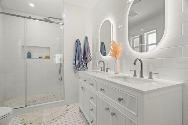 bathroom with vanity, toilet, tile walls, tasteful backsplash, and a shower with shower door