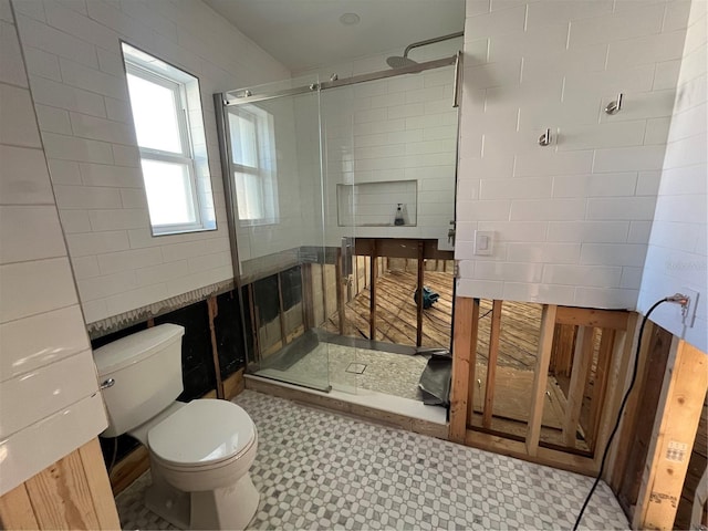 bathroom featuring a shower with shower door and toilet