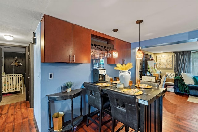 kitchen with a breakfast bar area, kitchen peninsula, dark hardwood / wood-style flooring, and decorative light fixtures