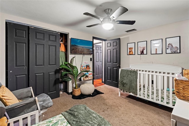 carpeted bedroom with a nursery area and ceiling fan