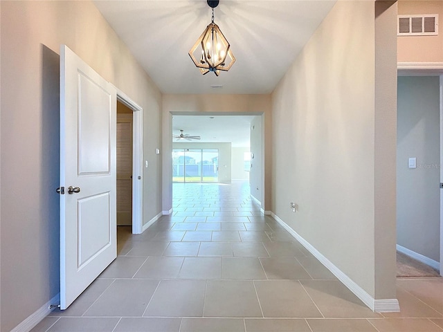 hall with tile patterned flooring and a chandelier