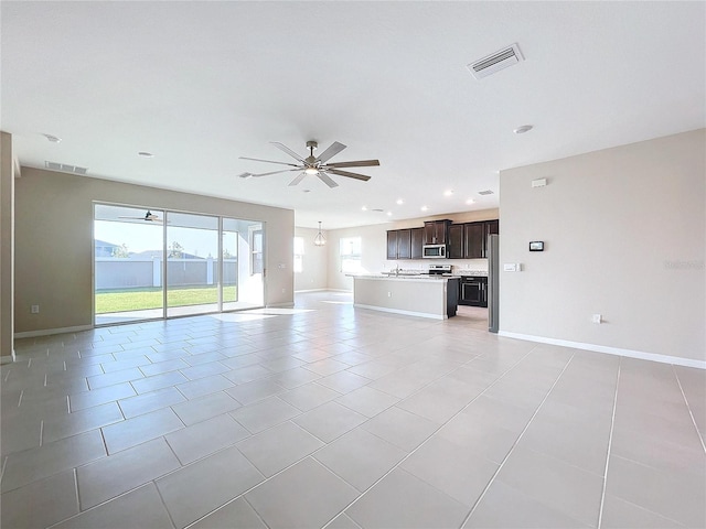 unfurnished living room with ceiling fan, a healthy amount of sunlight, and light tile patterned floors