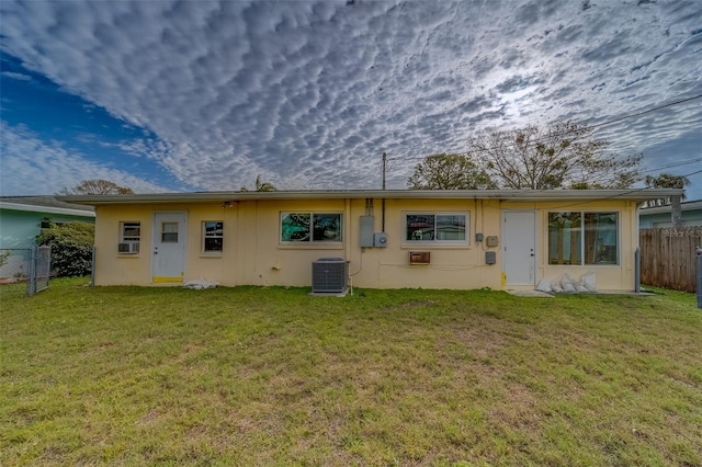 rear view of house featuring a lawn and cooling unit