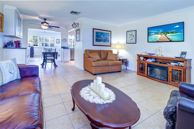 tiled living room featuring ceiling fan and crown molding