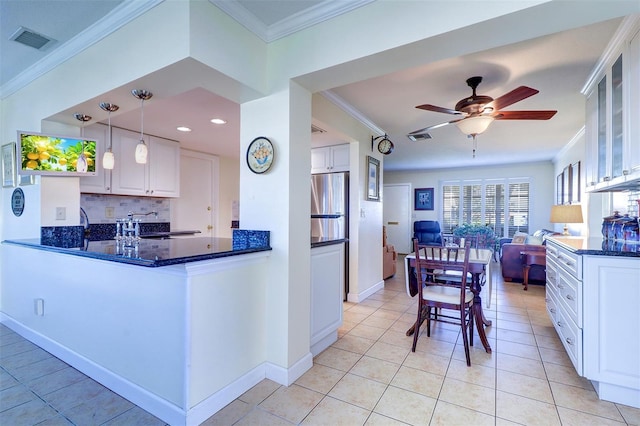 kitchen with pendant lighting, stainless steel fridge, tasteful backsplash, light tile patterned flooring, and white cabinetry