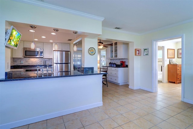 kitchen featuring dark stone counters, light tile patterned floors, decorative light fixtures, kitchen peninsula, and stainless steel appliances