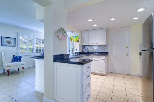 kitchen with white cabinets, backsplash, sink, and stainless steel refrigerator