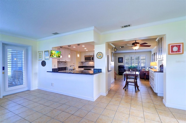 kitchen featuring light tile patterned floors, white cabinetry, hanging light fixtures, and crown molding