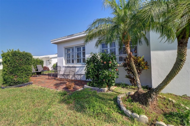 view of property exterior with a lawn and a patio