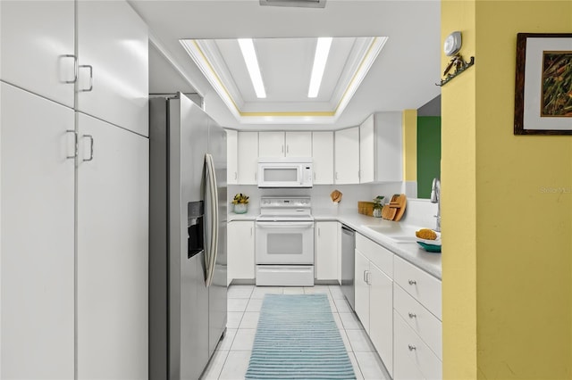 kitchen with stainless steel appliances, a raised ceiling, crown molding, sink, and white cabinetry