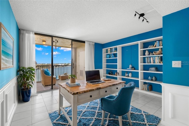 office area featuring a textured ceiling, floor to ceiling windows, light tile patterned floors, and rail lighting