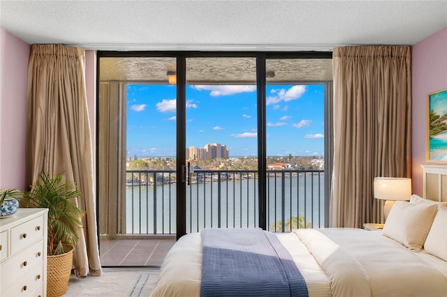 bedroom with multiple windows, access to outside, expansive windows, and a water view