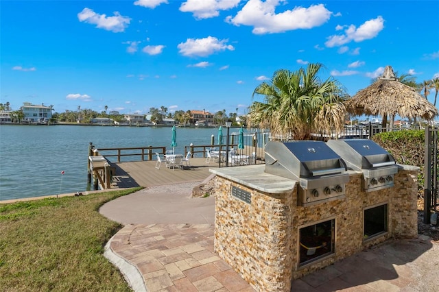 view of dock with a deck with water view, a patio area, and exterior kitchen