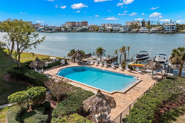 view of swimming pool featuring a boat dock, a water view, and a patio