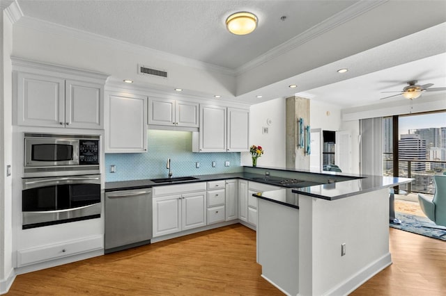 kitchen featuring kitchen peninsula, sink, white cabinets, and appliances with stainless steel finishes